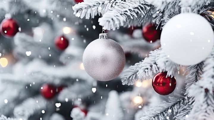Bild mit schneebedecktem Tannenbaum an dem Weihnachtskugeln hängen